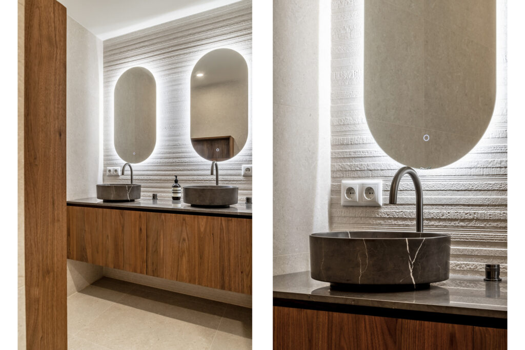 Modern bathroom with wooden vanities and oval mirrors.