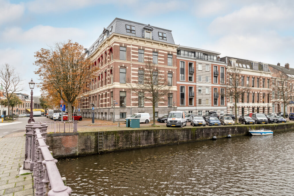 Historic building by canal with parked cars.