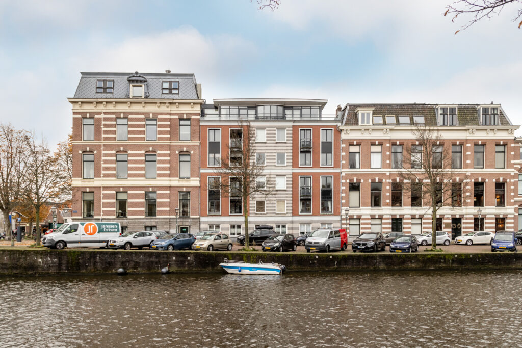 Historic buildings by canal with parked cars