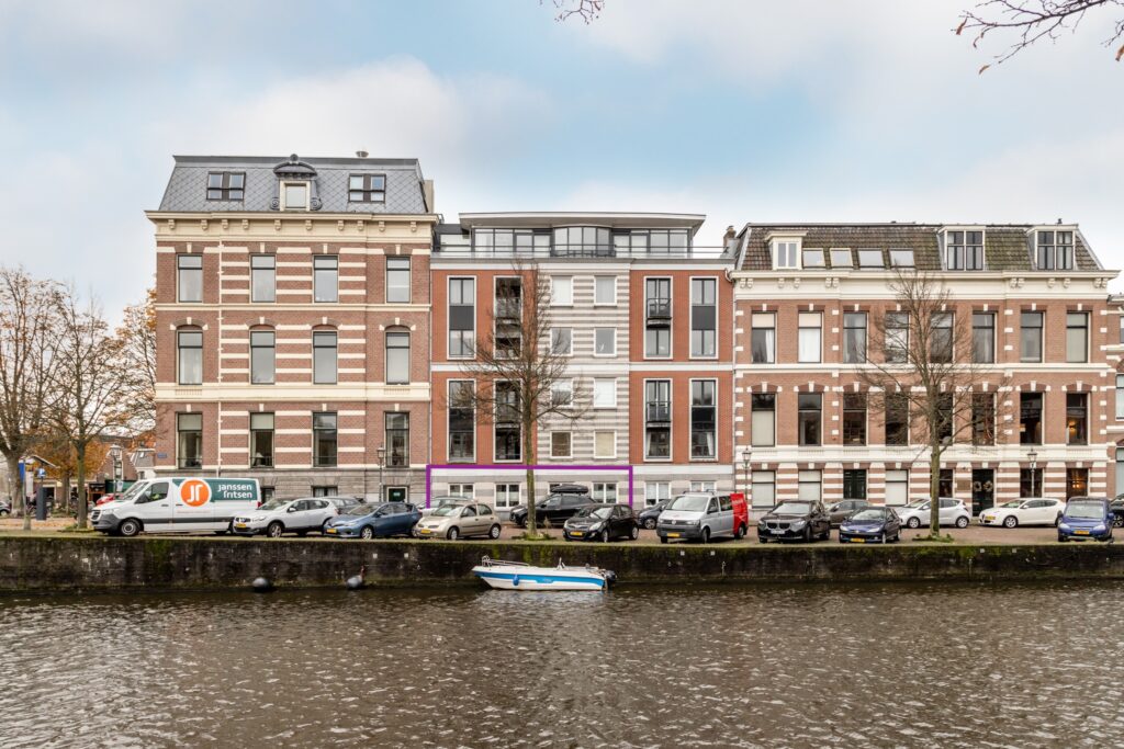 Riverfront building with parked cars and small boat.