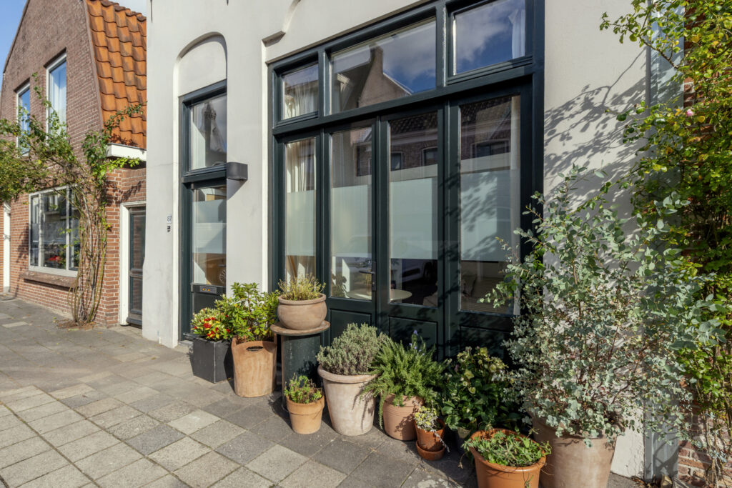 Charming house exterior with potted plants on sidewalk.