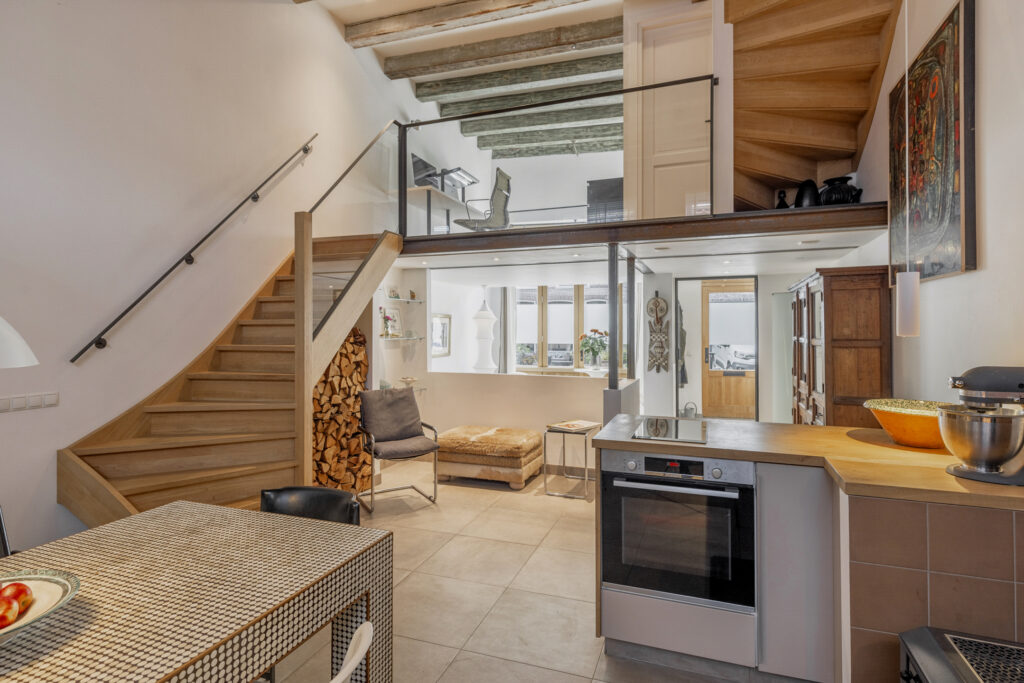 Modern loft interior with wooden staircase and kitchen.