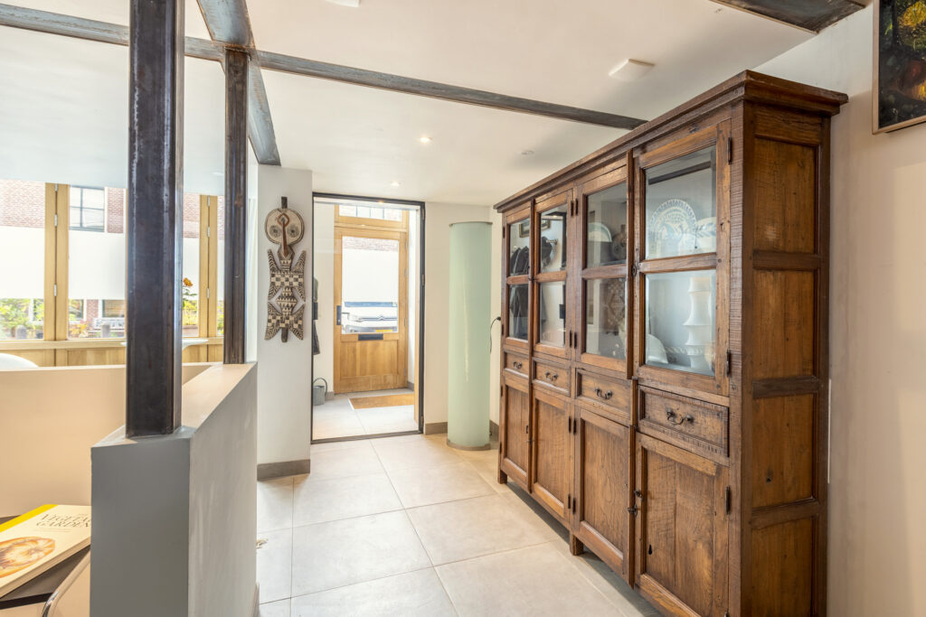 Spacious hallway with wooden cabinet and tribal mask.