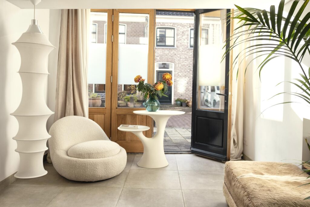 Cozy room with chair, table, flowers, and open door.