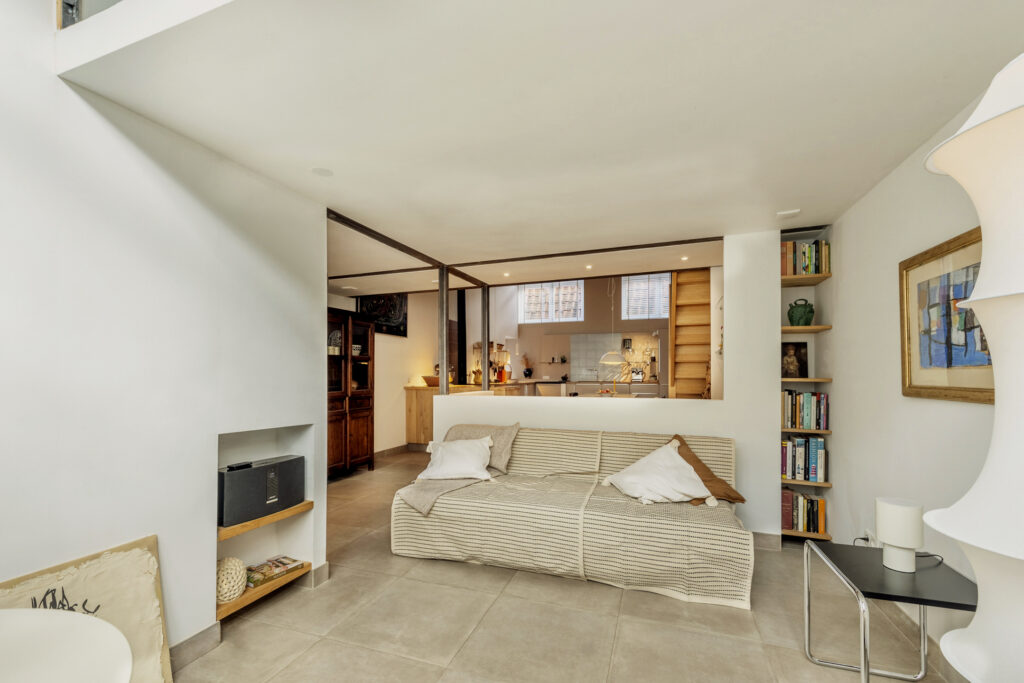 Modern living room with neutral decor and bookshelf.