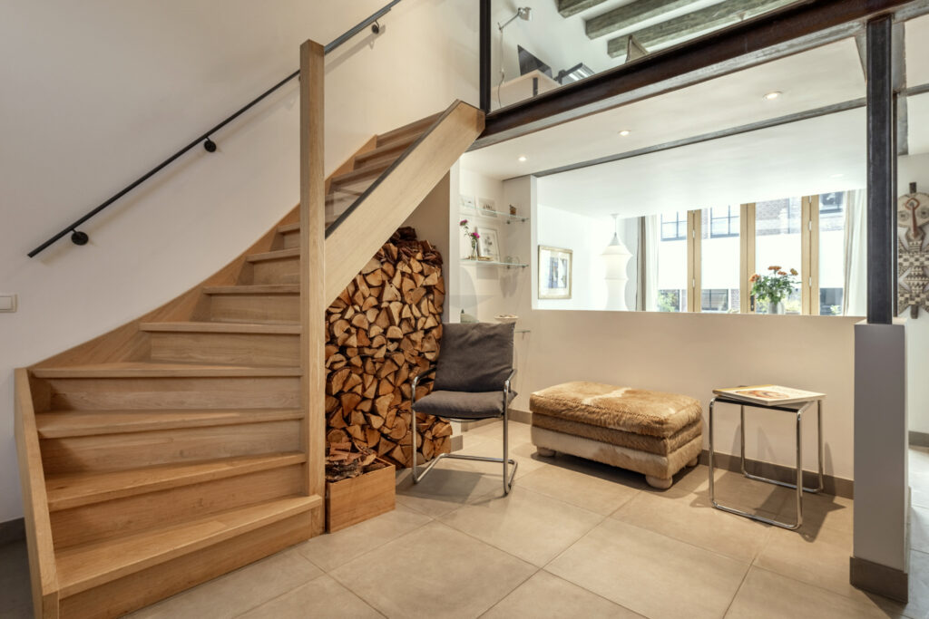Modern living room with staircase and firewood storage.