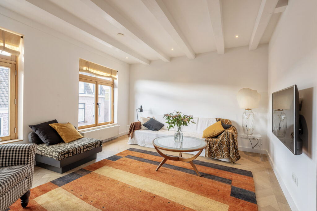 Modern living room with vibrant orange rug.