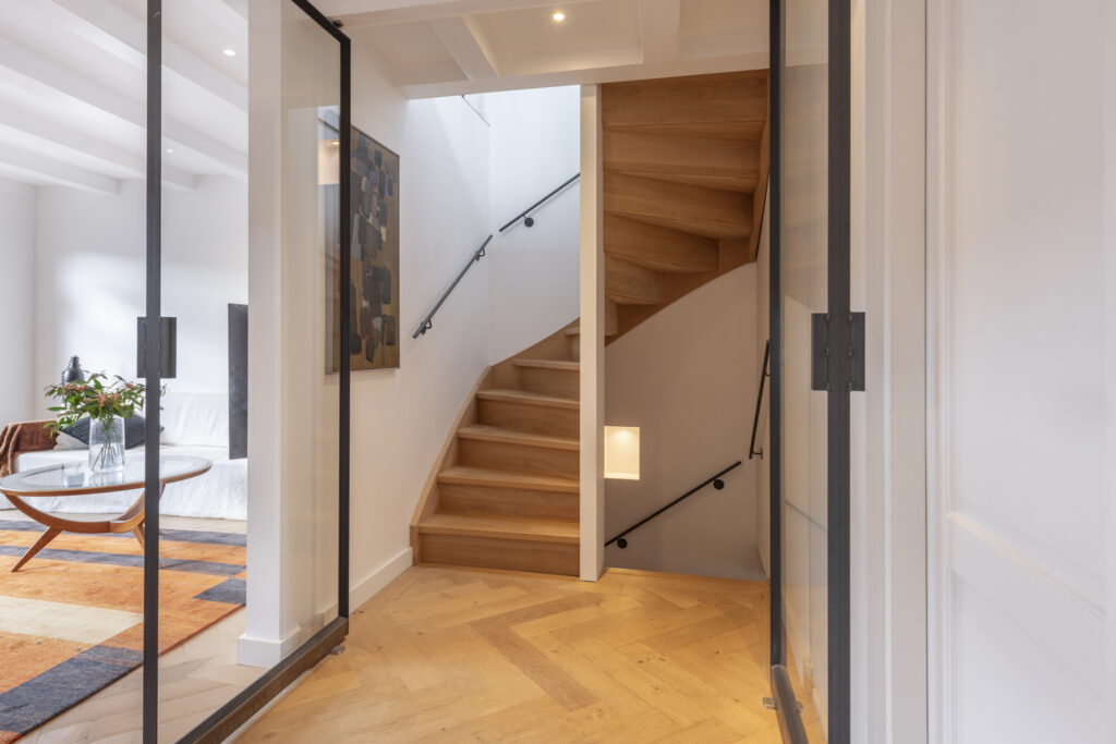 Modern wooden staircase with cozy living area view.