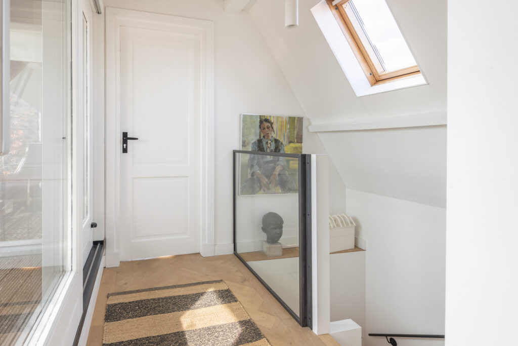 Bright hallway with painting and bust, skylight above.