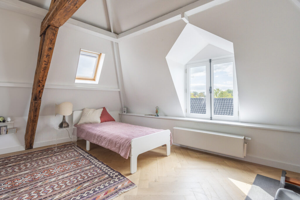 Cozy attic bedroom with skylight and window view.