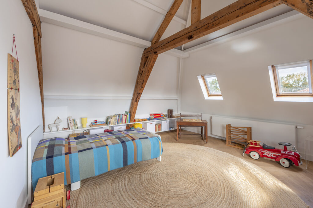 Cozy attic bedroom with wooden beams and skylights.