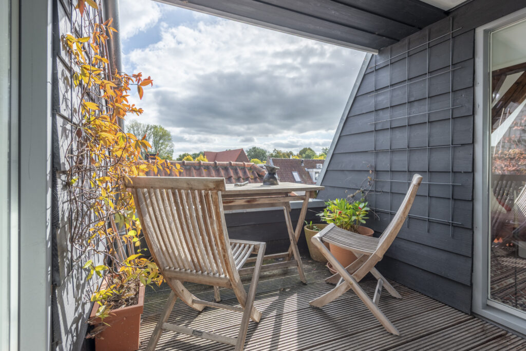 Cozy rooftop patio with chairs and plants.