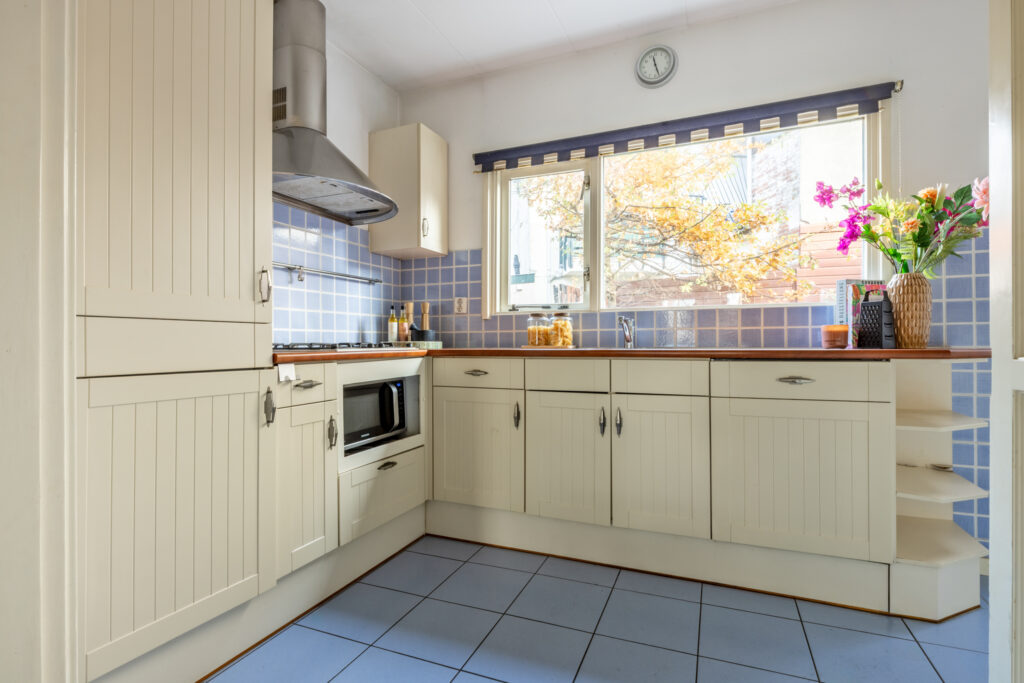 Bright kitchen with blue tiles and flowers.