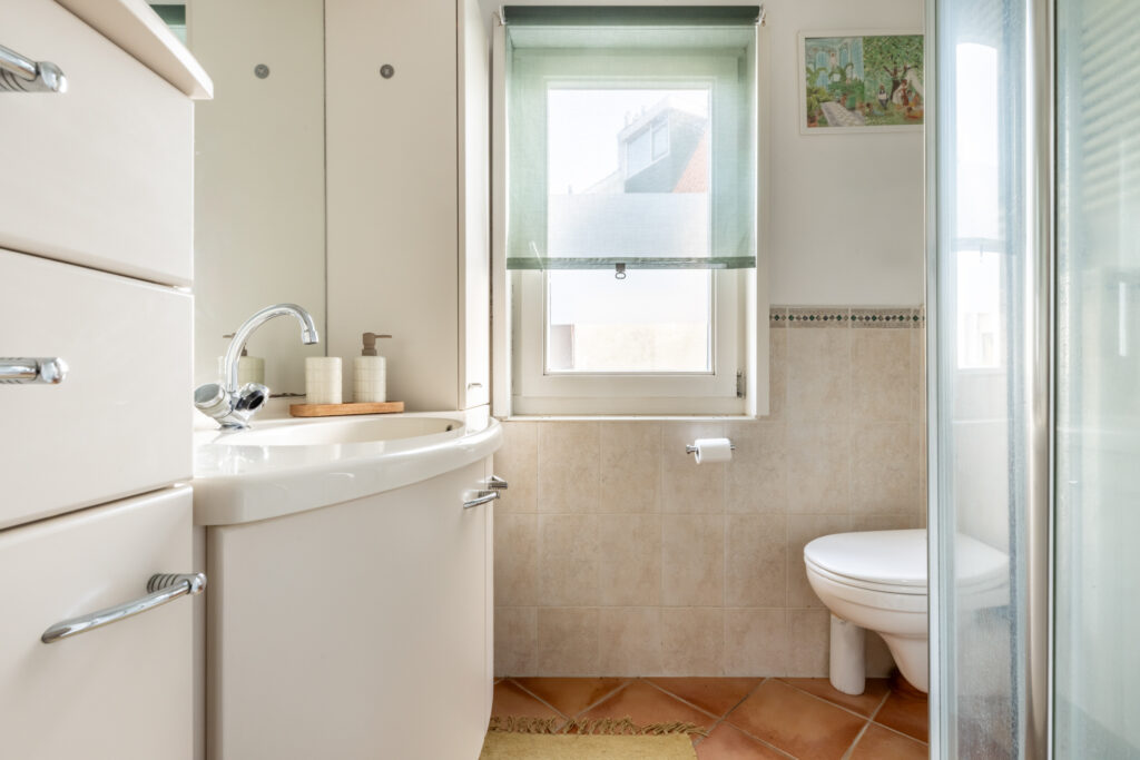 Sunny bathroom with sink, toilet, and window.