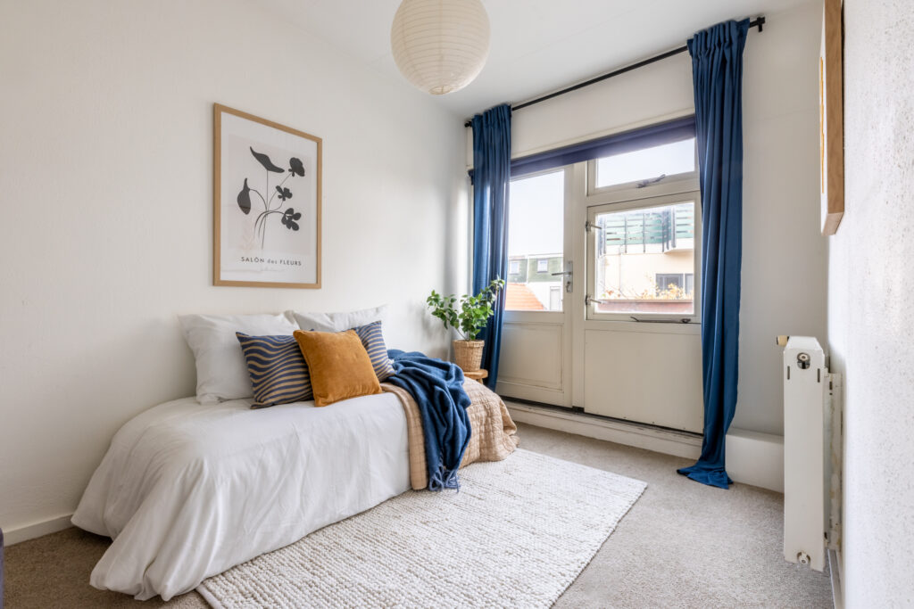 Cozy bedroom with blue curtains and modern decor.
