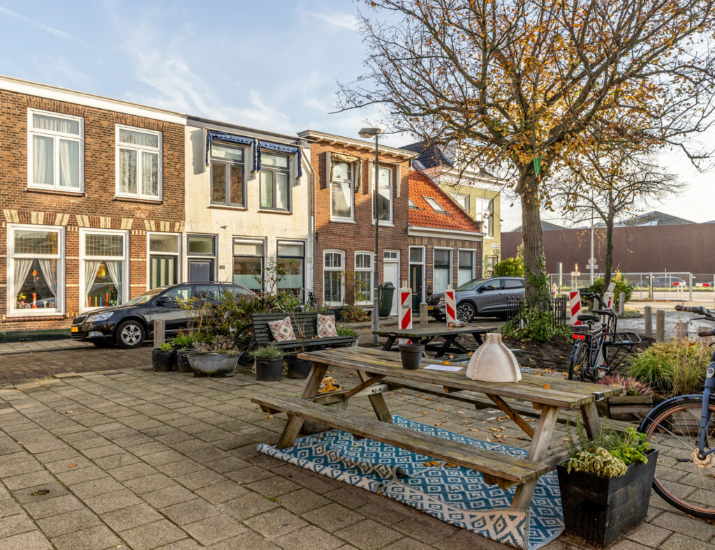 Quiet street with parked cars and picnic tables.
