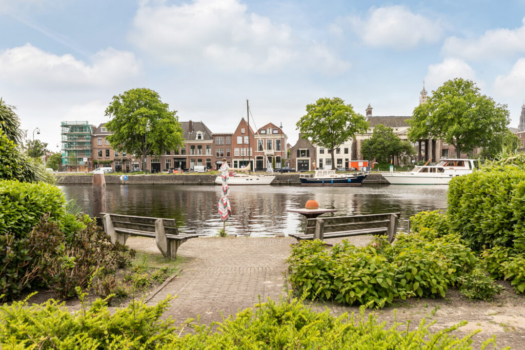 Benches by a river with boats and buildings.