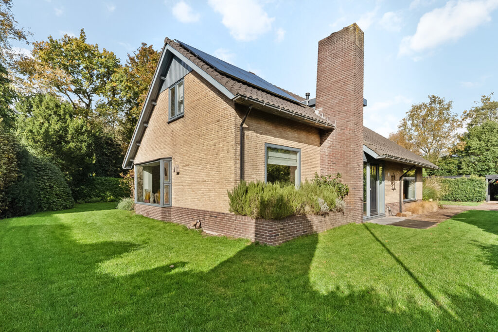 Charming brick house with green lawn and trees.