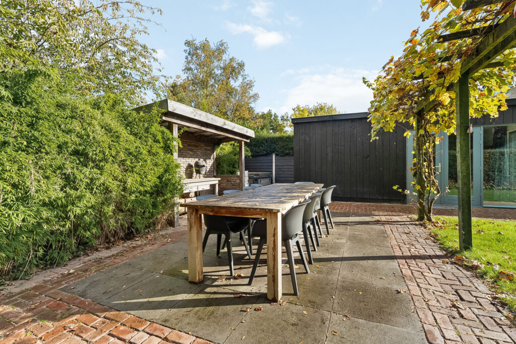 Outdoor patio with table, chairs, and greenery.