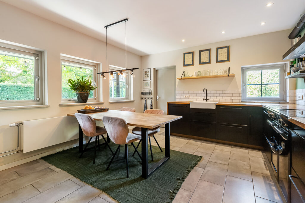 Modern kitchen with wooden table and black cabinets.