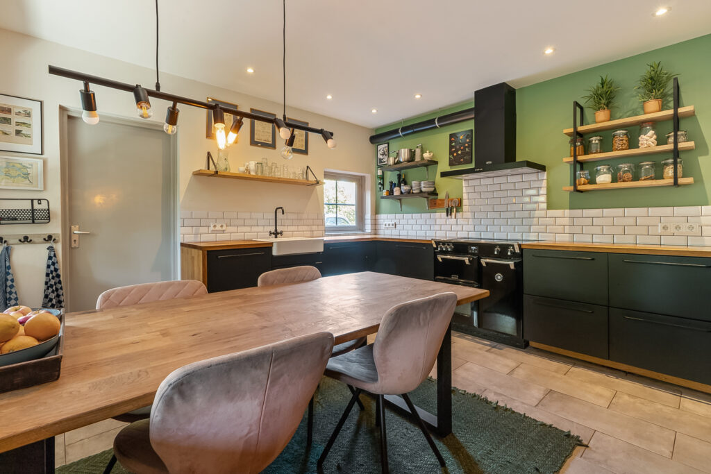 Modern kitchen with wood table and green walls.