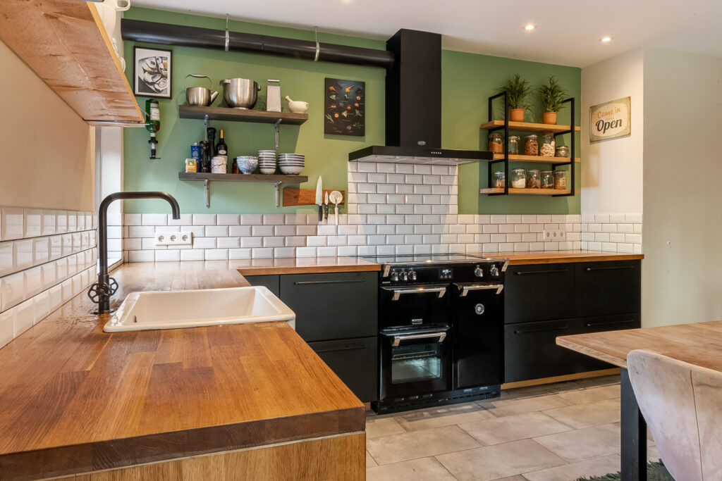Modern kitchen with green walls and wooden countertops.