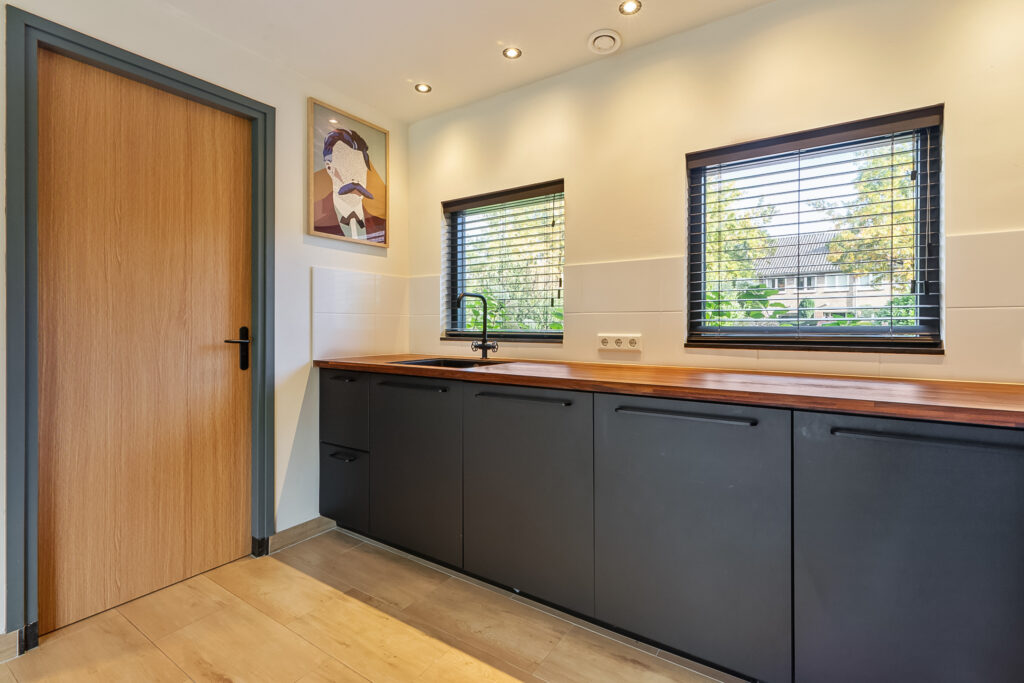 Modern kitchen with wood counters and art.