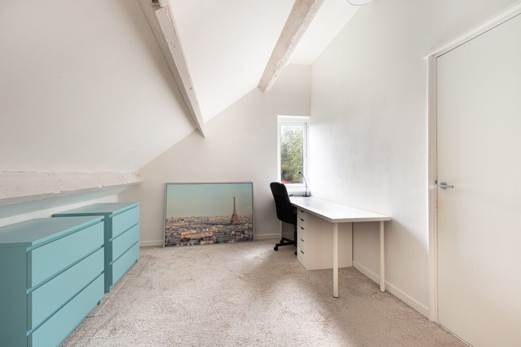 Minimalist attic office with desk and drawers.
