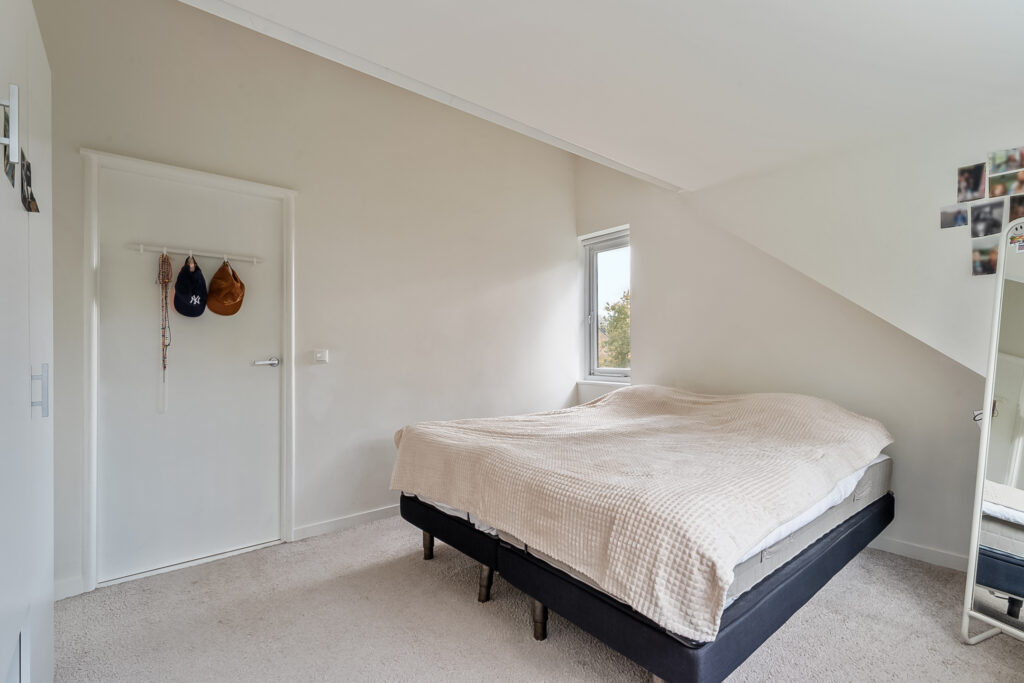 Minimalist bedroom with bed, hats on door