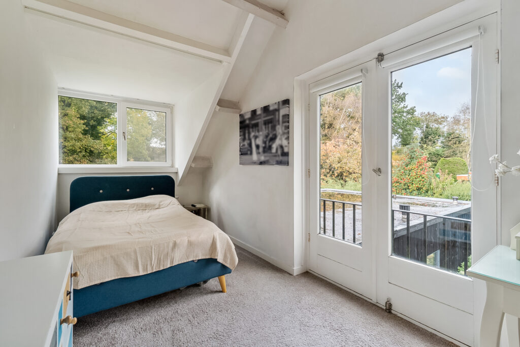 Cozy bedroom with large window and forest view.