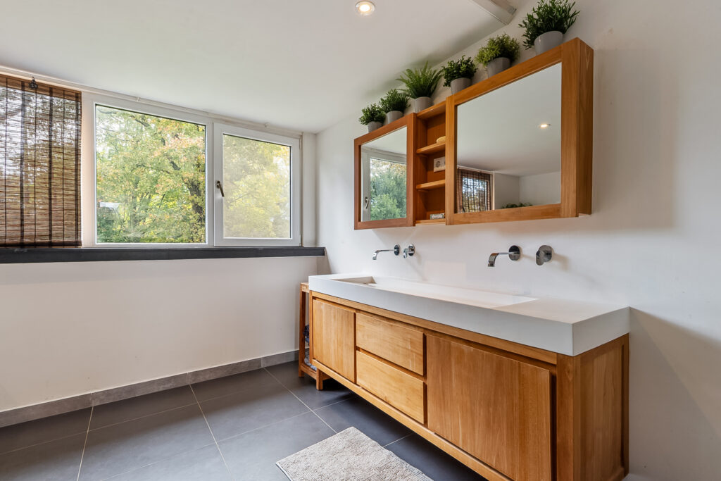 Modern bathroom with large windows and wooden cabinets.