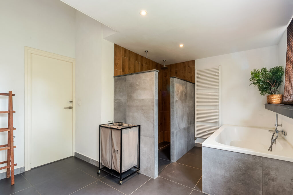 Modern bathroom with shower, bathtub, and storage.