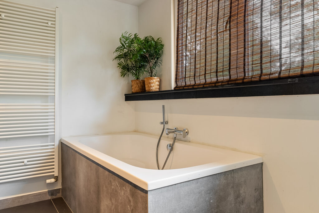 Modern bathroom with bathtub and plants.
