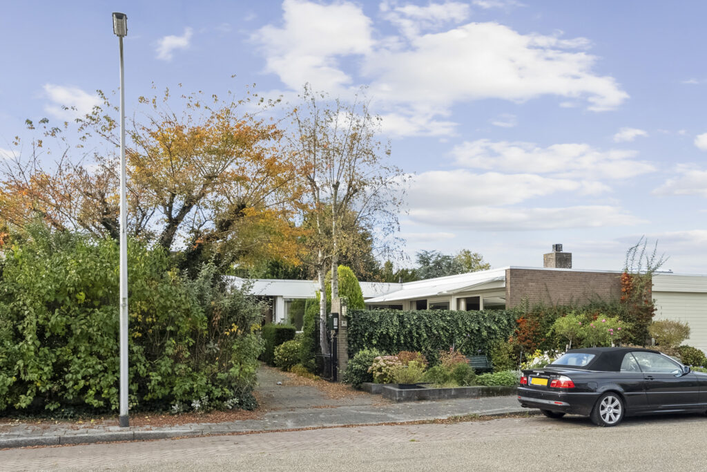 Suburban house with garden and parked car on street.