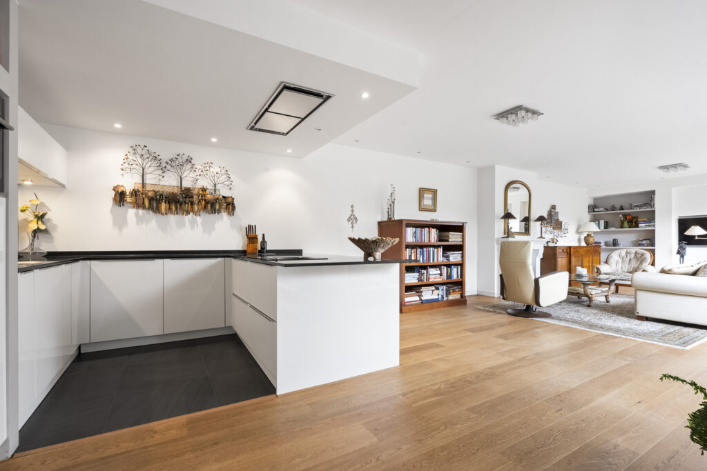 Spacious modern living room with white kitchen.