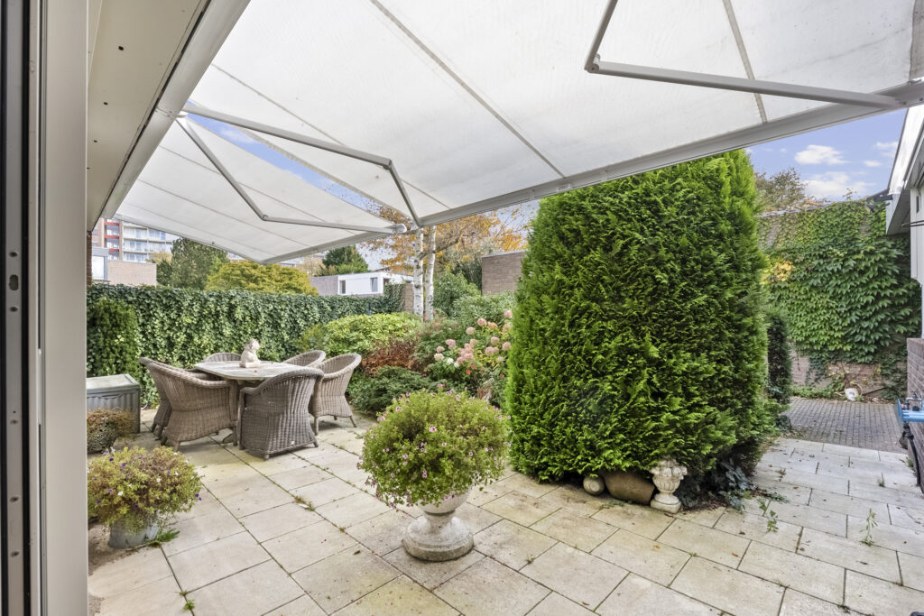 Backyard patio with awning and garden view.
