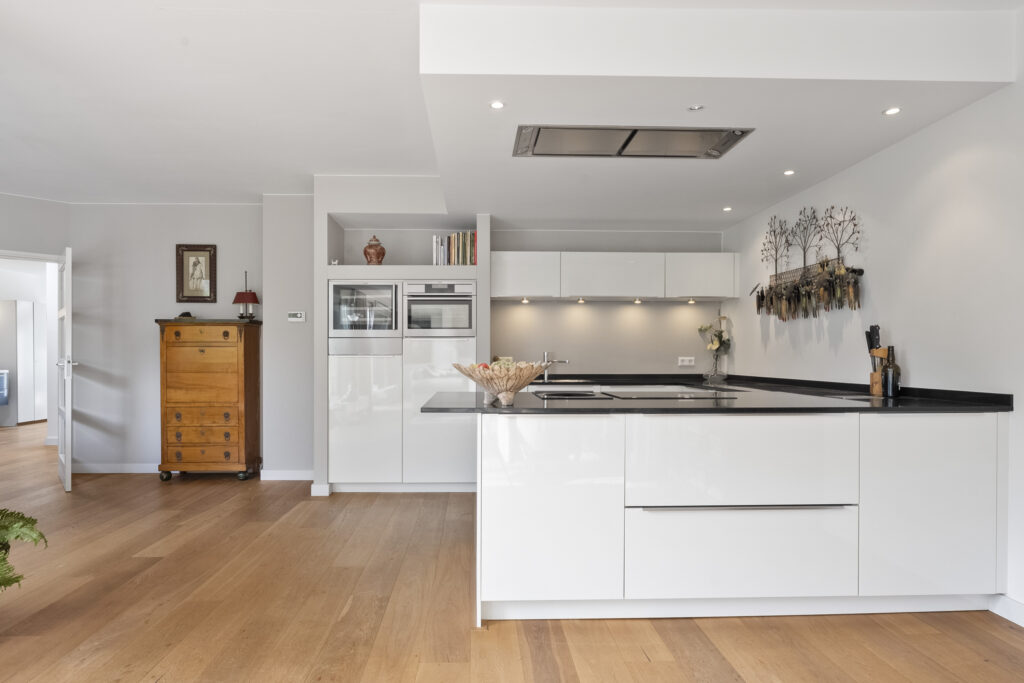 Modern kitchen with white cabinets and wooden floor.