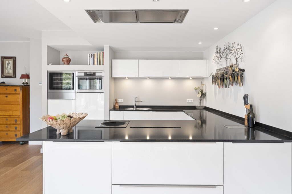 Modern kitchen with white cabinets and black countertops.