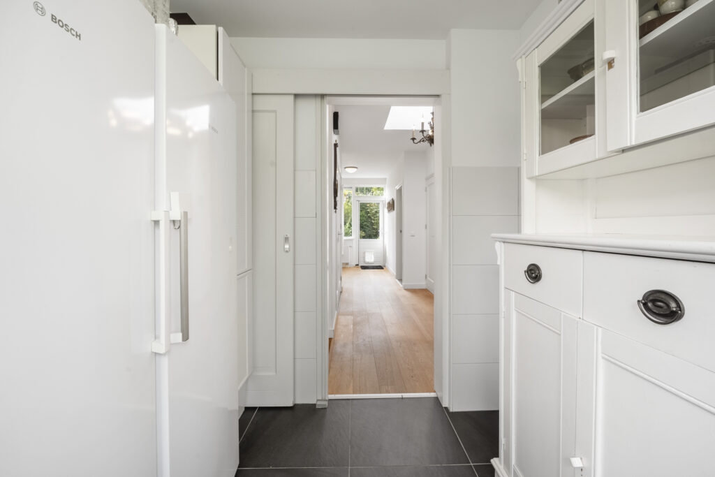 Modern kitchen with white cabinets and wooden floor.