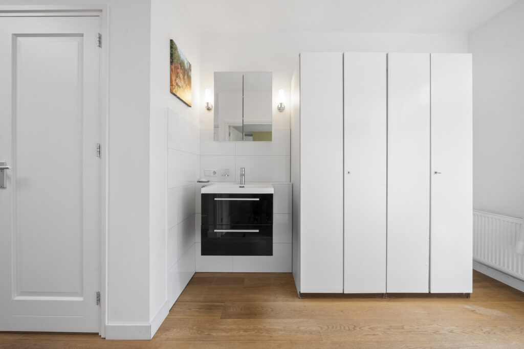 Modern bathroom with white cabinets and wooden floor.