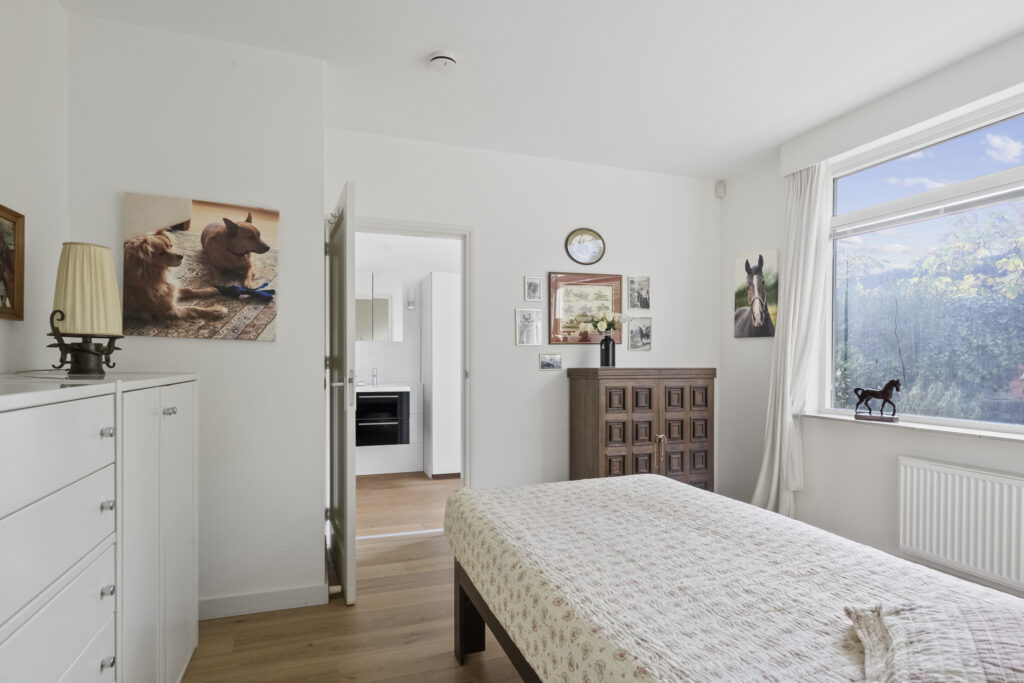 Cozy bedroom with bed, dresser, and art on walls.