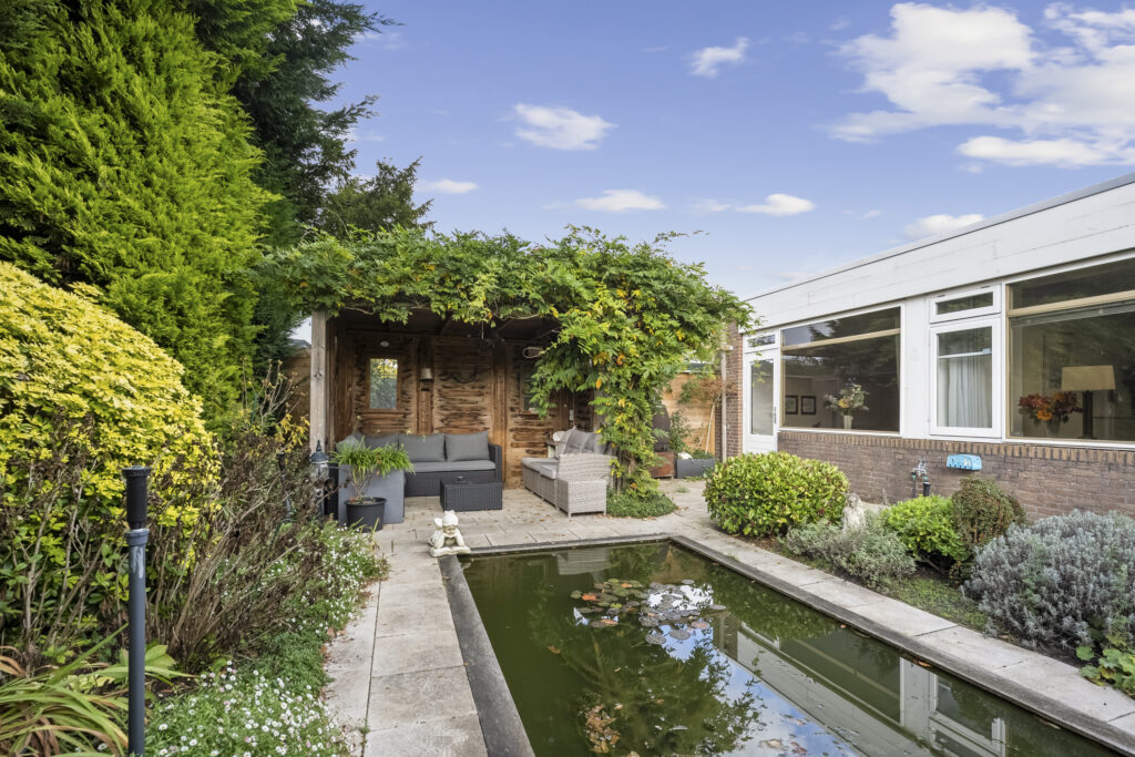 Cozy backyard patio with garden and pond.