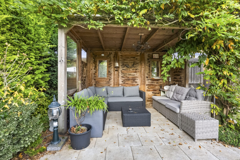 Cozy outdoor patio with wicker furniture and greenery.