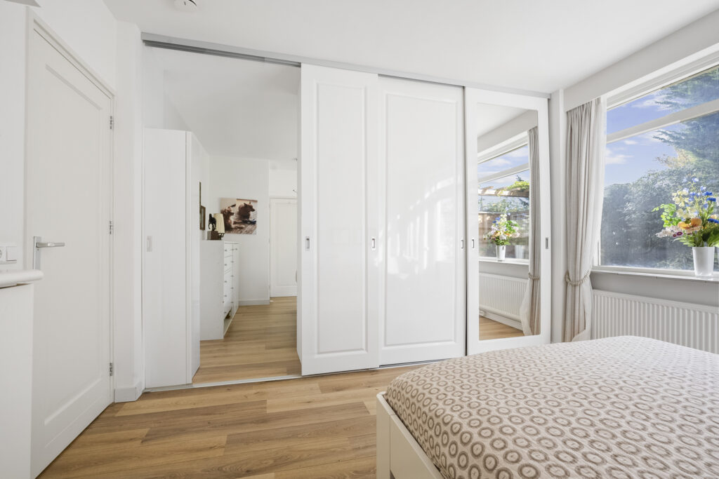 Bright bedroom with mirrored closet and large window