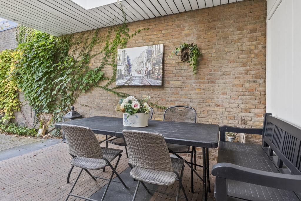 Outdoor patio with ivy and art on brick wall.