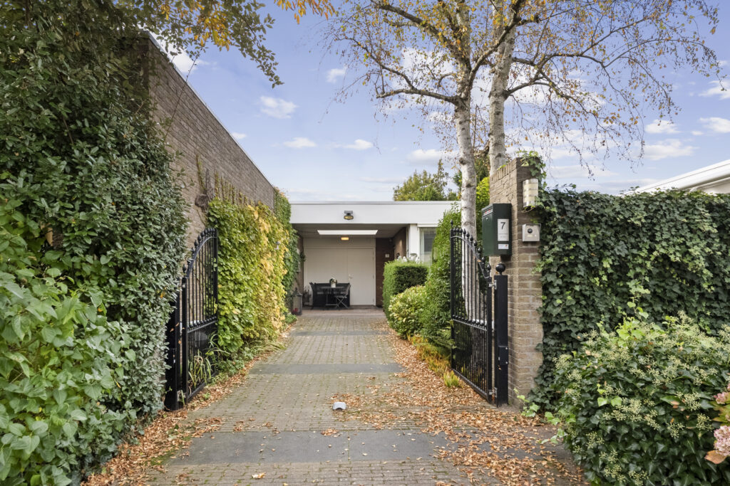 Gated driveway with green ivy-covered walls.