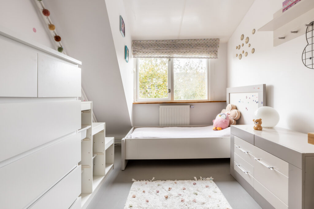 Cozy child's bedroom with white furniture and toys.