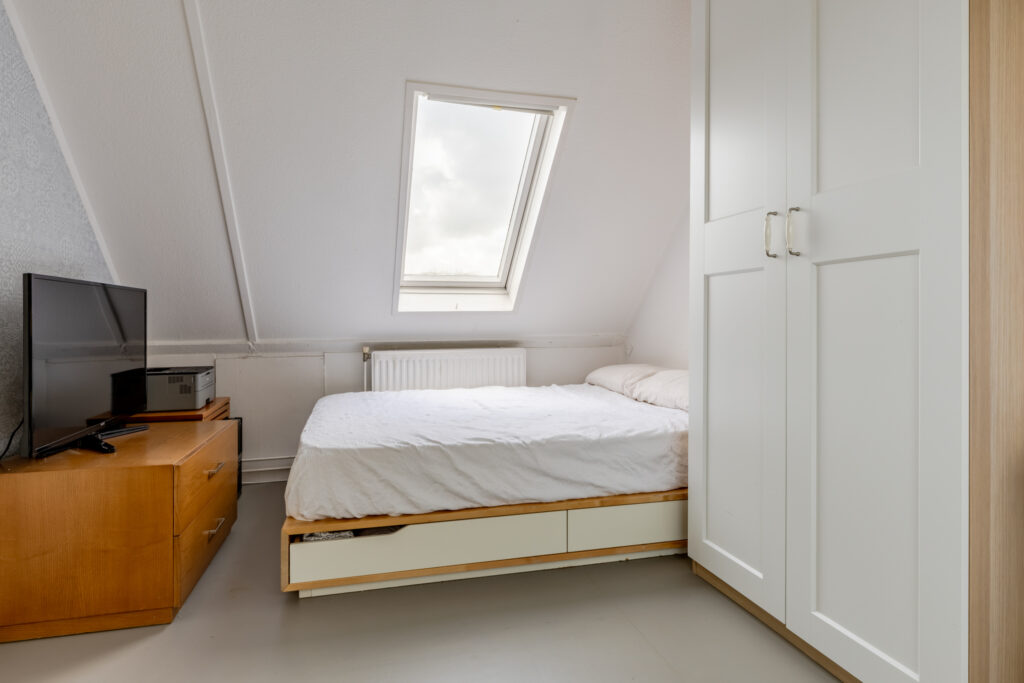 Attic bedroom with bed, wardrobe, and TV.
