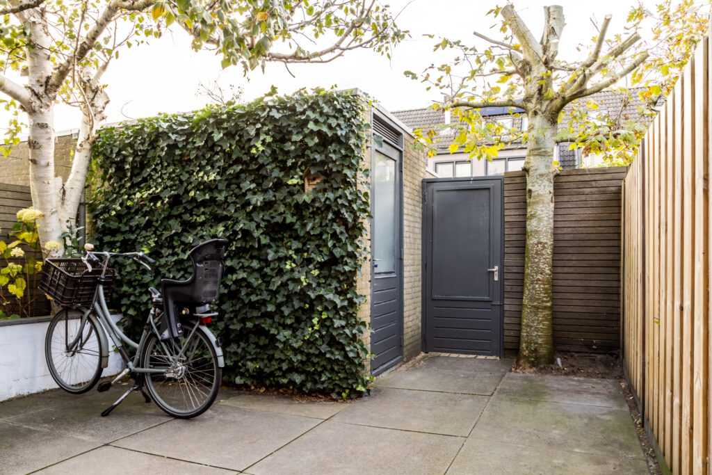 Bike parked by ivy-covered wall in courtyard.