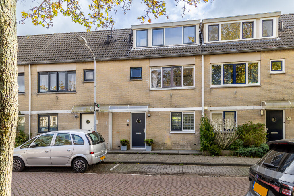 Residential street with cars and row houses.